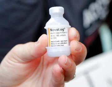 A close-up of a person's hand holding up a vial of insulin.