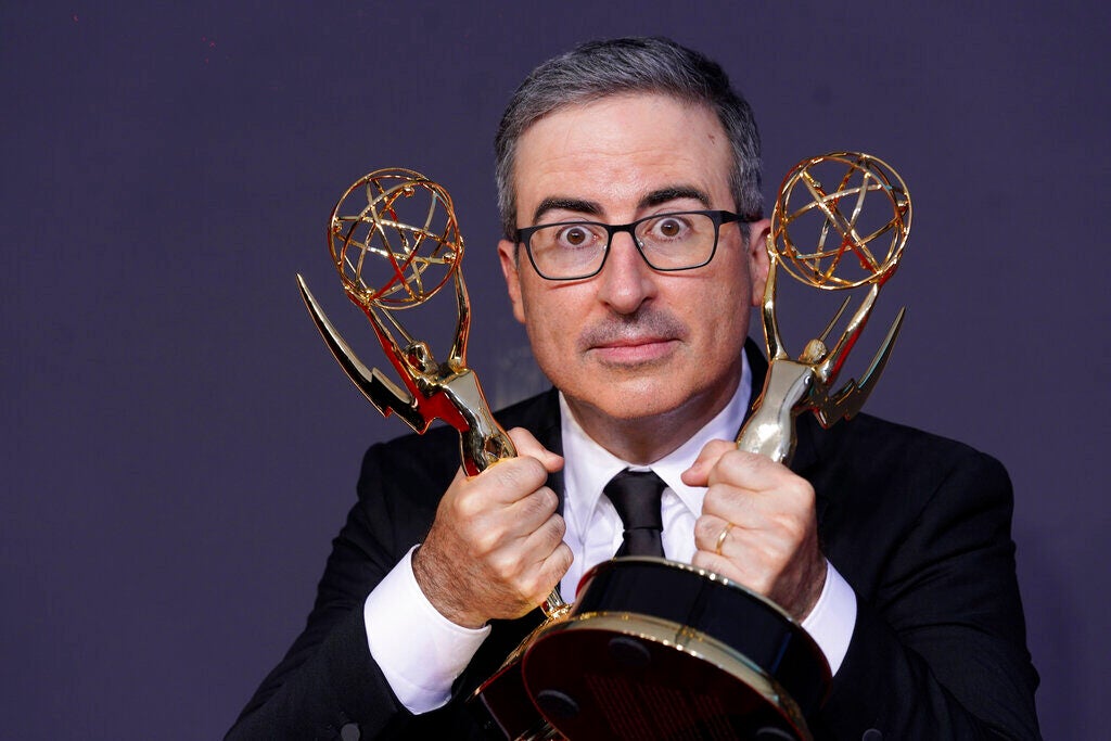 John Oliver poses for a photo with awards in hand