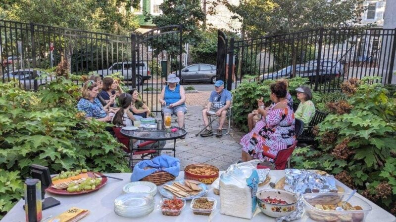 A group of people sitting outside with a spread of food on the table