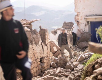 People stand on the rubble left behind from an earthquake in Morocco.