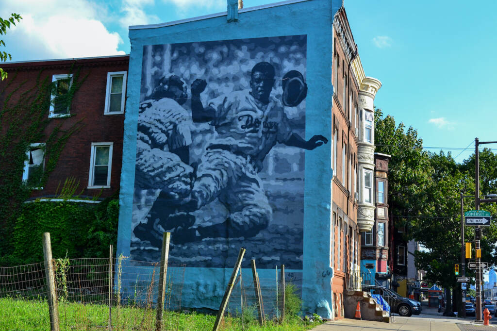 A large mural, showing Jackie Robinson stealing home on the side of a building