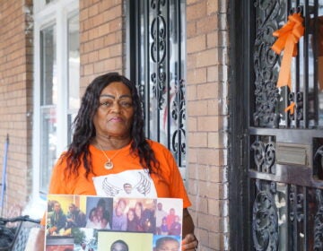 Yullio Robbins carries a sign and wears a shirt with images of her son, James.