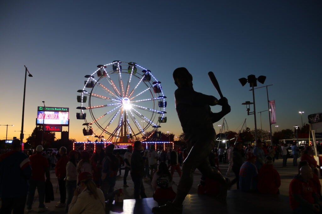 A statue of a baseball player is seen against the night sky