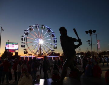 A statue of a baseball player is seen against the night sky