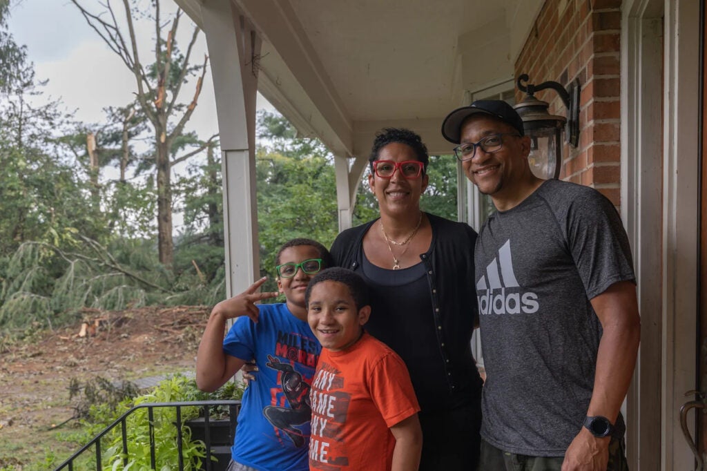 Cat and Robert Tucker with their sons Miles and Austin on their porch in Chadds Ford Township in August, 2023, after a heavy storm with strong straight winds destroyed trees on their property. 