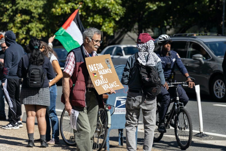 A protester holds a sign that says 'Media silence = Israeli violence'