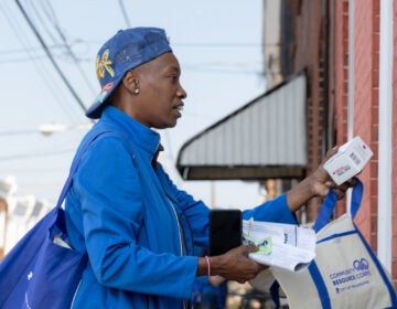 Marsella Elie, a canvasser for Philly Counts, gives opioid overdose reverse drug Narcan to a North Philadelphia resident as part of an initiative with the city’s Office of Community Empowerment and Opportunity to get harm reduction resources into homes in areas heavily hit by the opioid crisis. (Kimberly Paynter/WHYY)