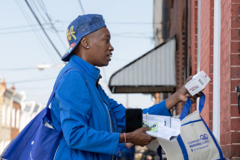 Marsella Elie, a canvasser for Philly Counts, gives opioid overdose reverse drug Narcan to a North Philadelphia resident as part of an initiative with the city’s Office of Community Empowerment and Opportunity to get harm reduction resources into homes in areas heavily hit by the opioid crisis. (Kimberly Paynter/WHYY)