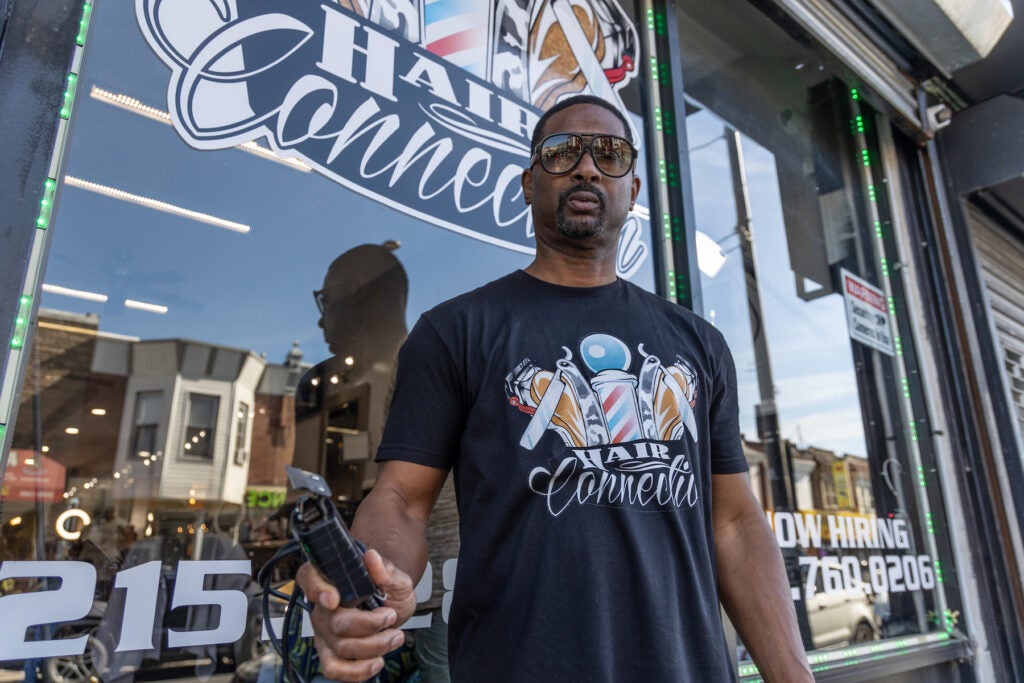 Fred Hill posing with hair clippers in front of his shop.