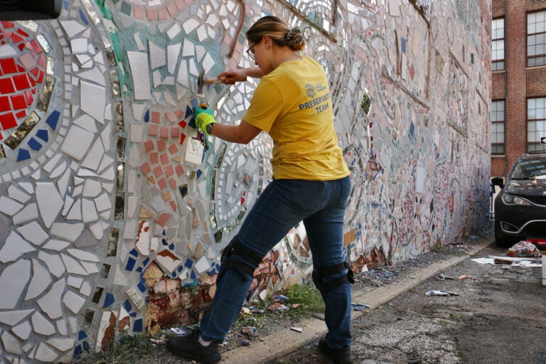 Volunteer Amanda Zelinger chisels tiles off the facade of the Painted Bride Art Center