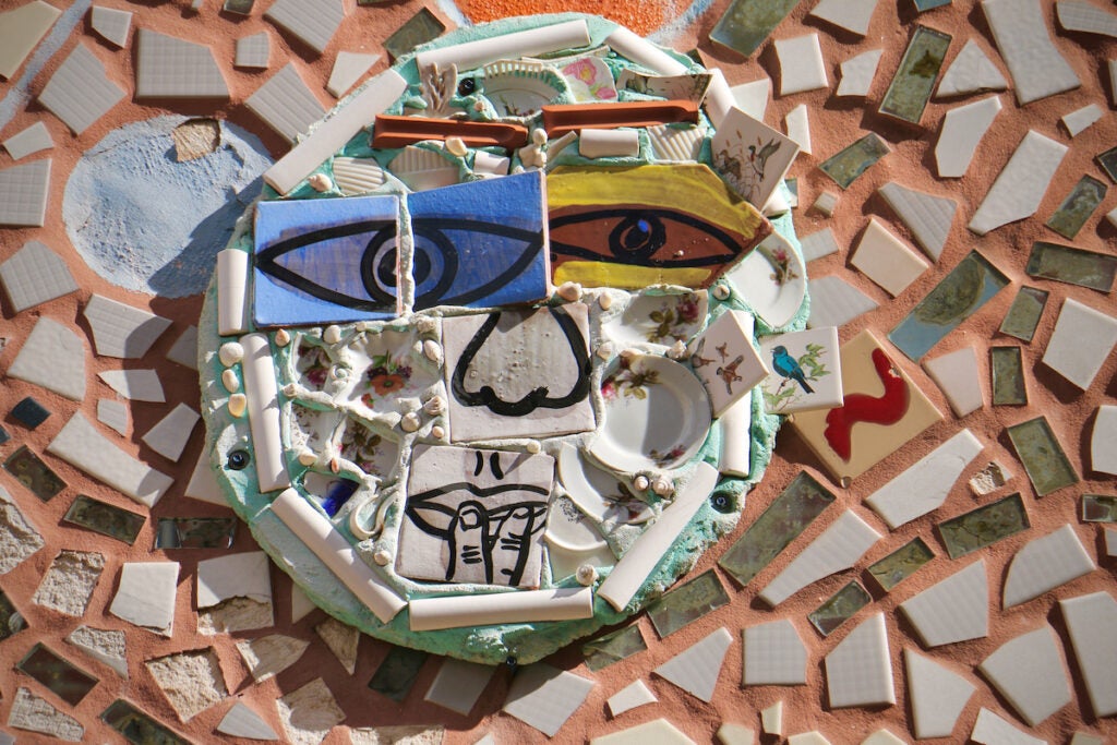 An up-close view of a face made of different artworks in the midst of a larger mosaic.
