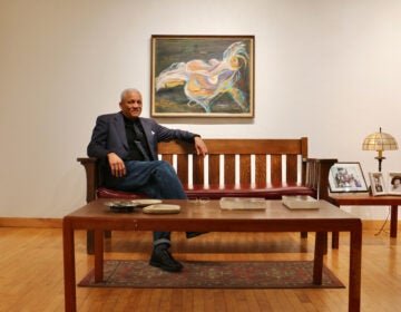 Mark Rollins sitting on a bench. A Dox Thrash painting in the background.