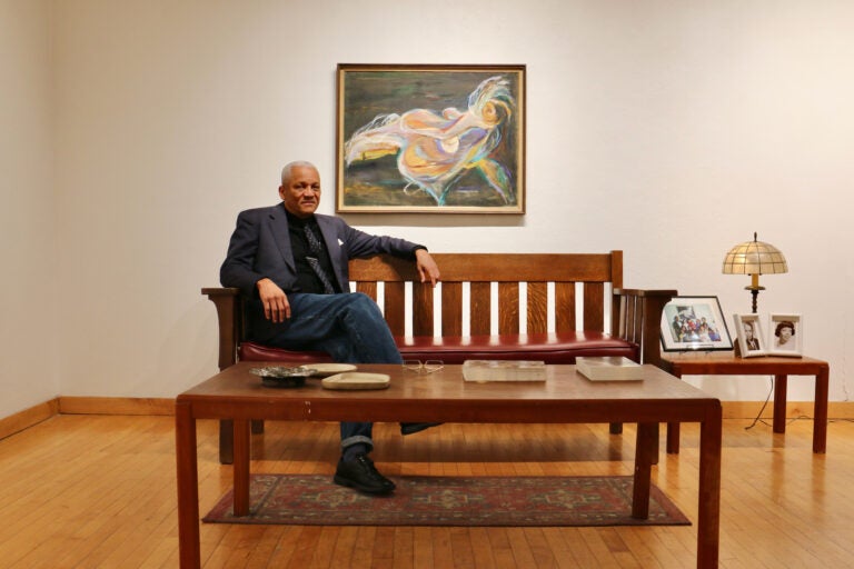 Mark Rollins sitting on a bench. A Dox Thrash painting in the background.