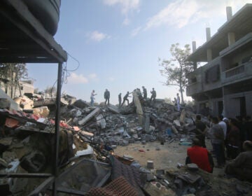 Palestinians stand by the building destroyed in an Israeli airstrike