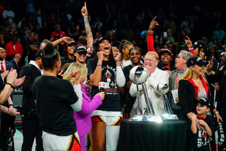 Las Vegas Aces' A'ja Wilson and Mark Davis celebrate with teammates next to the trophy after Game 4 of a WNBA basketball final playoff series against the New York Liberty Wednesday, Oct. 18, 2023, in New York. The Aces won 70-69. (AP Photo/Frank Franklin II)