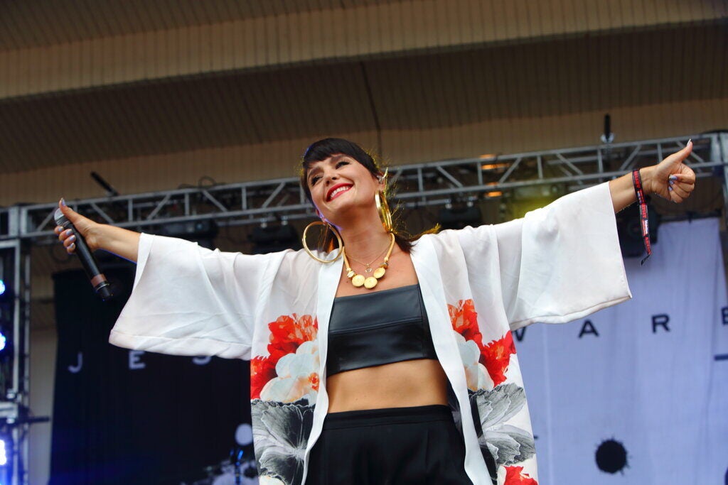 Jessie Ware smiles and spreads out her arms as she stands onstage