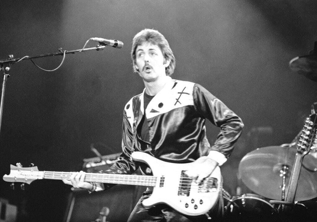 A black-and-white photo of Paul McCartney playing guitar onstage