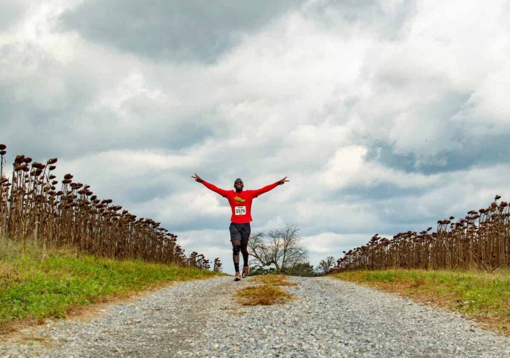 A person raises their arms up as they run on a pathway