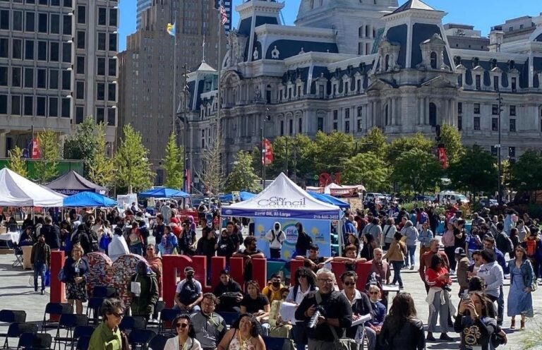 A view from above of a crowd of people and stands in LOVE Park. Philadelphia City Hall is visible in the background.