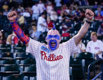 A Phillies fan with face painted cheering in the stands.