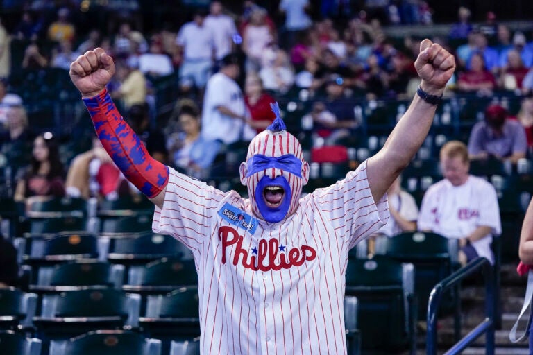 A Phillies fan with face painted cheering in the stands.