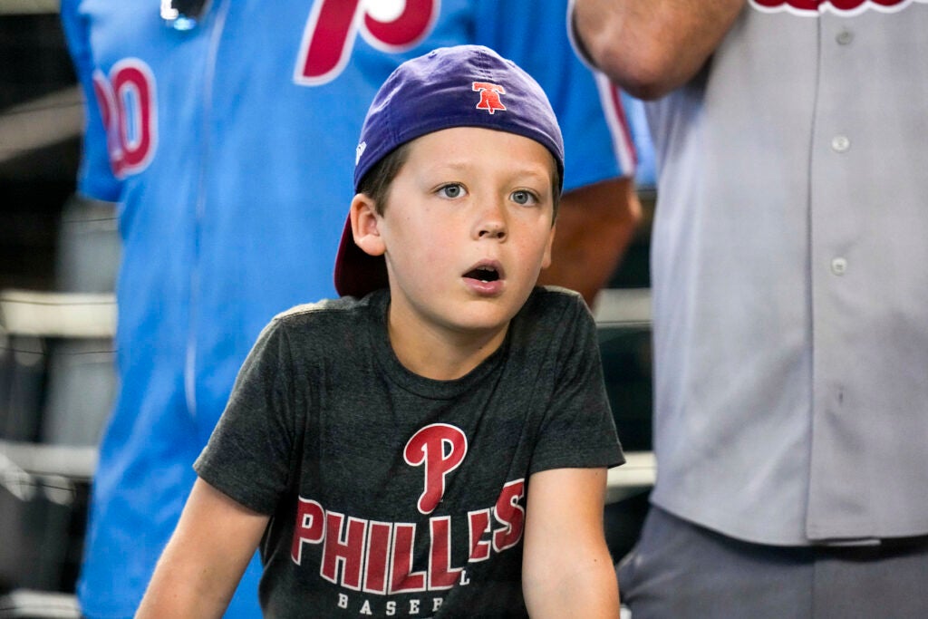 A young boy wearing Phillies hat and shirt at the game.