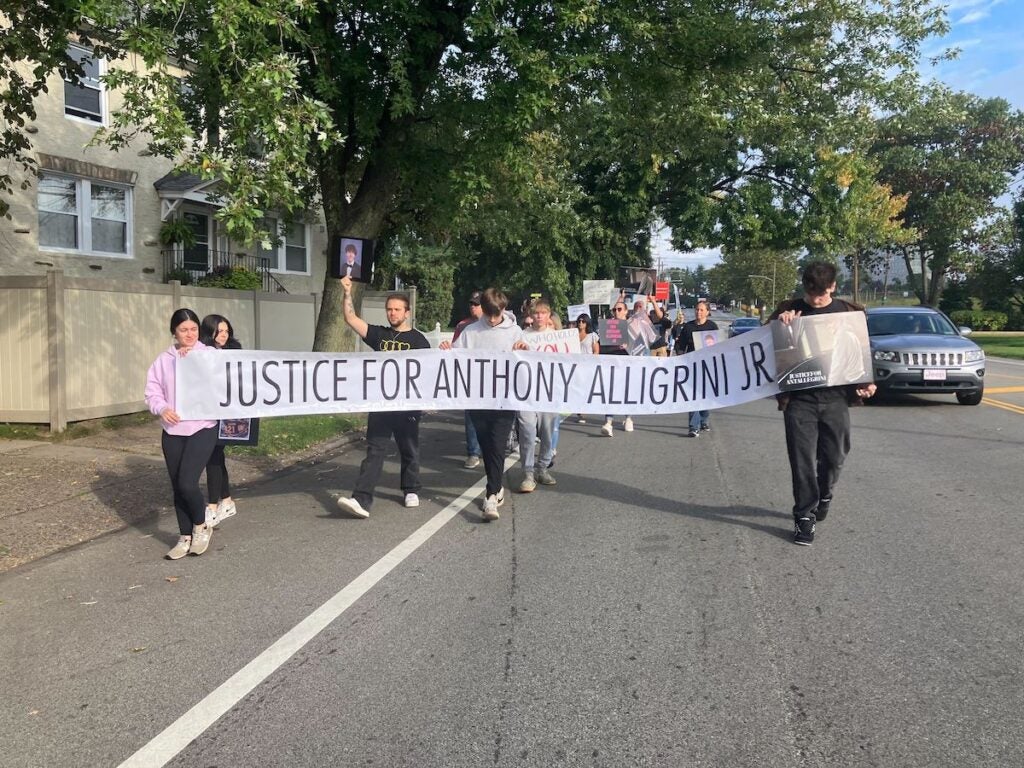 A group of people hold a banner that reads "Justice for Anthony Allegrini Jr."