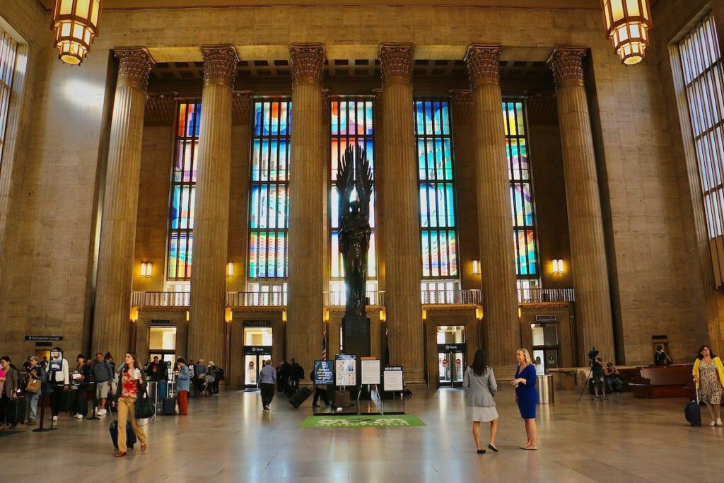 A statue and art installation in the windows of the train station are visible