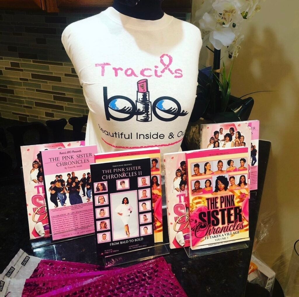 Copies of books are displayed on a table along with a T-shirt that reads Traci's BIO.