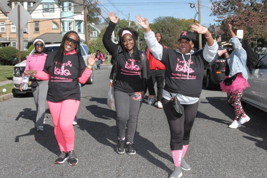 Traci's BIO team members raise their hands up and pose for a photo as they walk down the street.