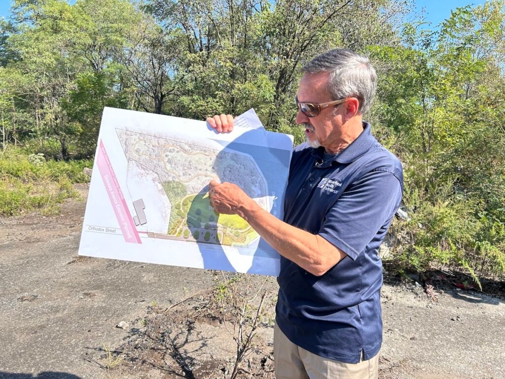 Jim Fries holds up a map and points towards it.