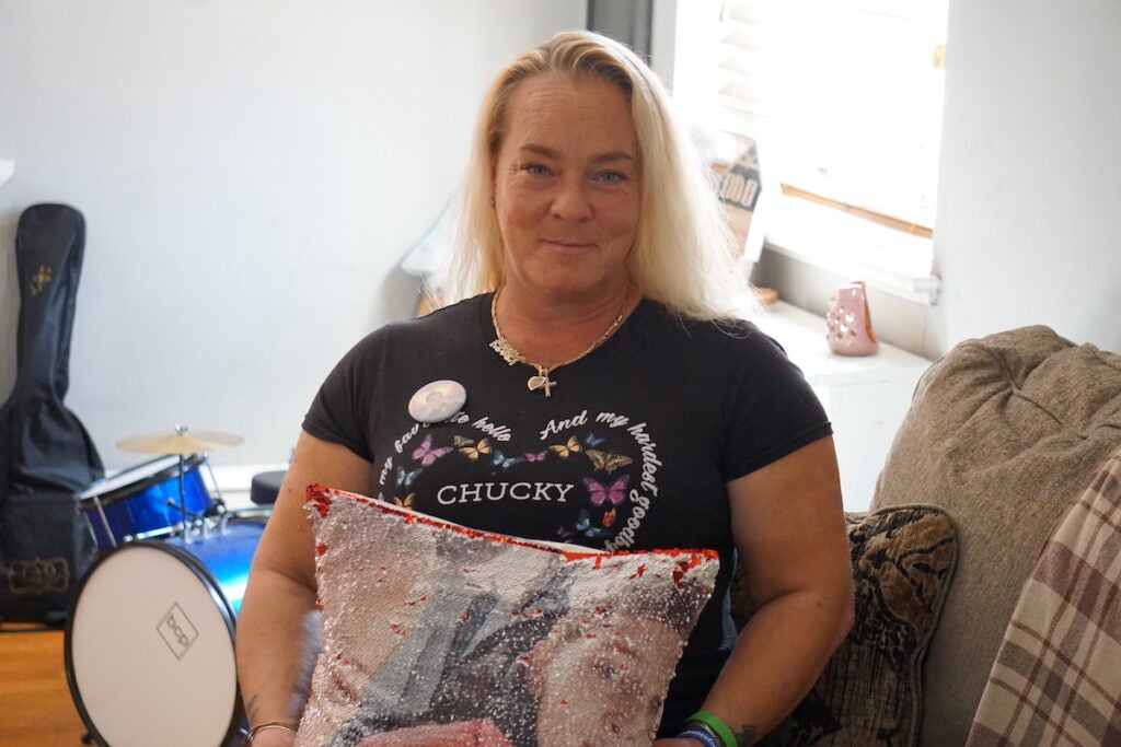 Jennifer Meleski wears a shirt that reads "Chucky" and holds a pillow.