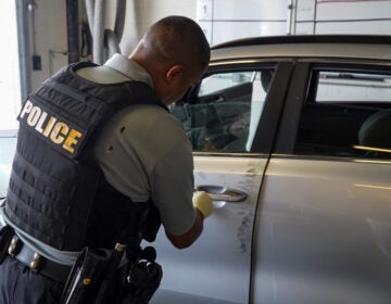 A New Castle County police officer processes a recovered stolen care in search of evidence.