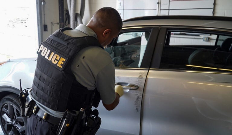 A New Castle County police officer processes a recovered stolen care in search of evidence.