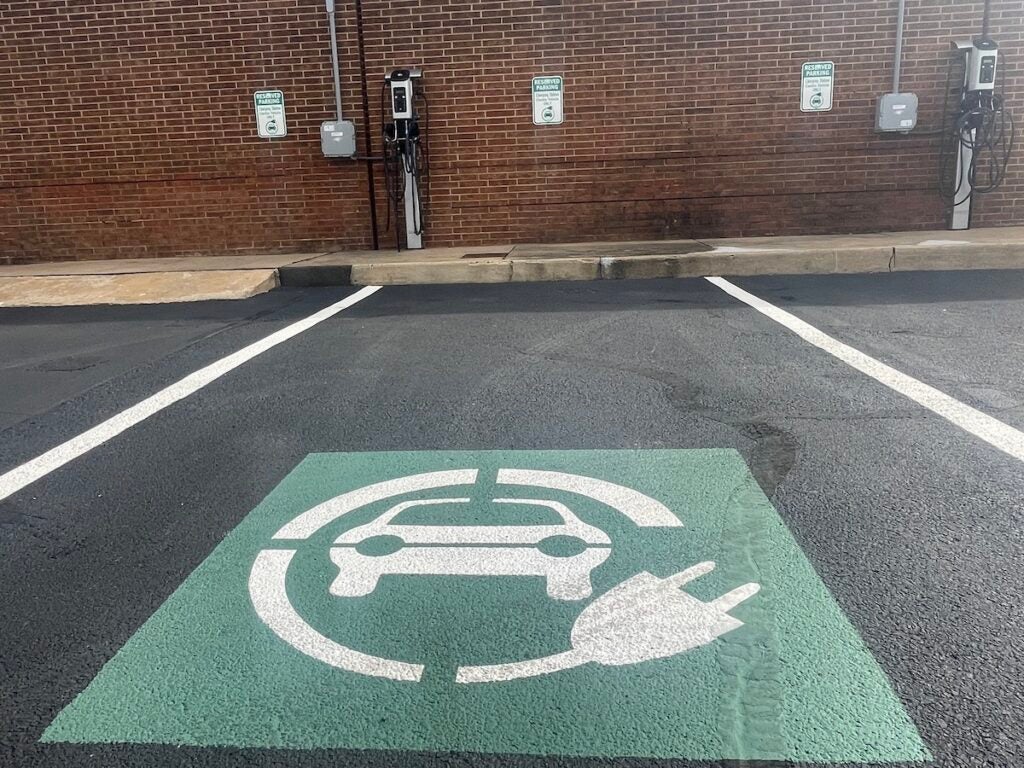 A parking spot in front of an EV charging station with a large green EV charging sign.