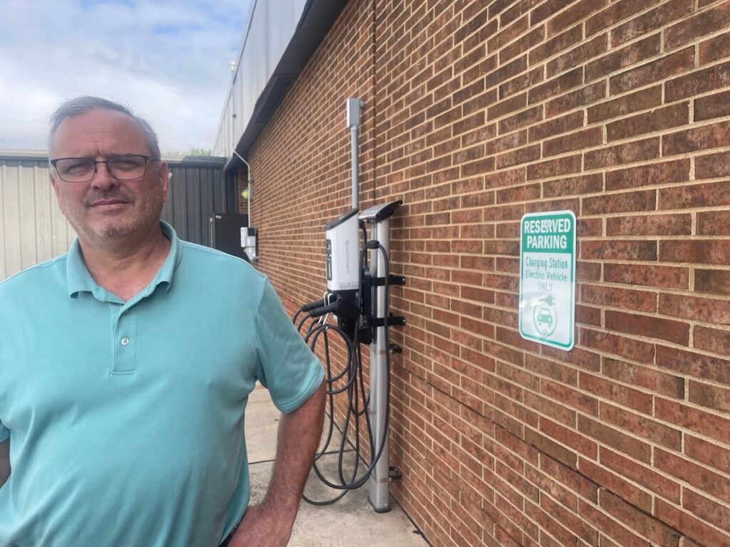 Dan Edelon poses for a photo in front of an EV charging station