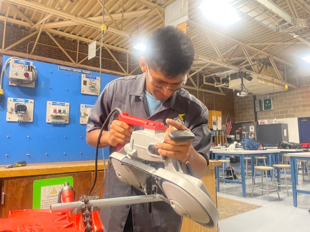 Aleksander Mirada-Vasquez works with a machine to cut piping.