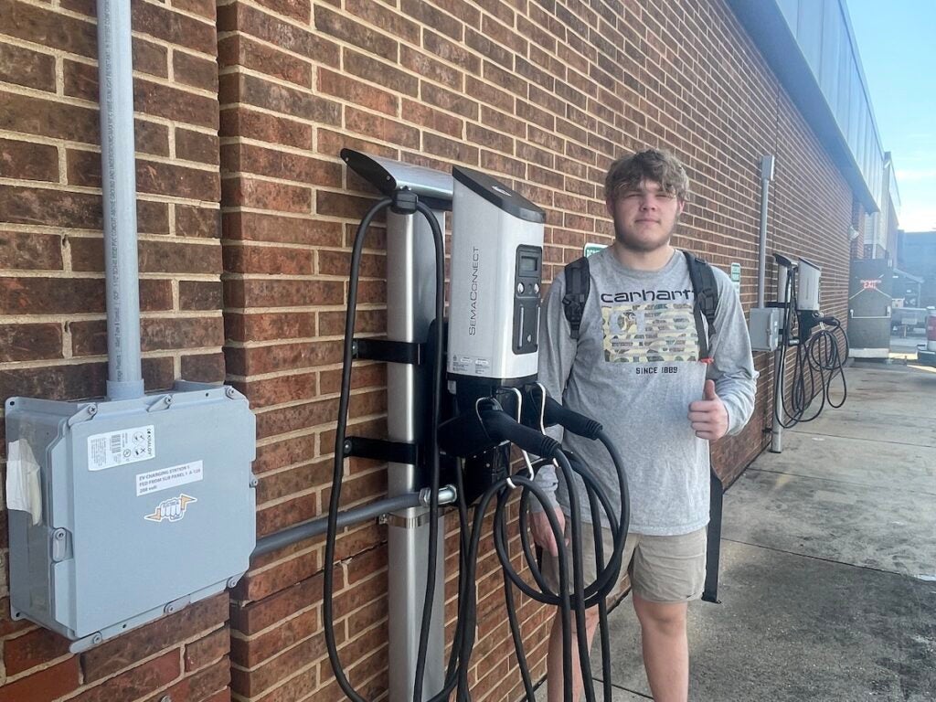 William Kisielewski poses for a photo next to an EV charging station.