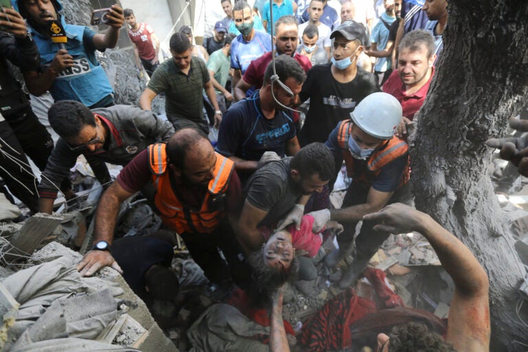 Palestinians rescue a child from under the rubble after Israeli airstrikes in Gaza City