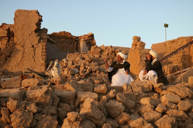 Afghan residents sit at a damaged house after an earthquake in a village in Herat province on Saturday.