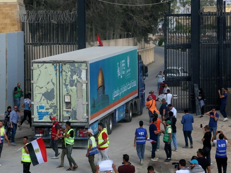 People on the Egyptian side of the Rafah border crossing watch as a convoy of lorries carrying humanitarian aid crosses to the Gaza Strip on Sunday.(Mohammed Assad/AFP via Getty Images)