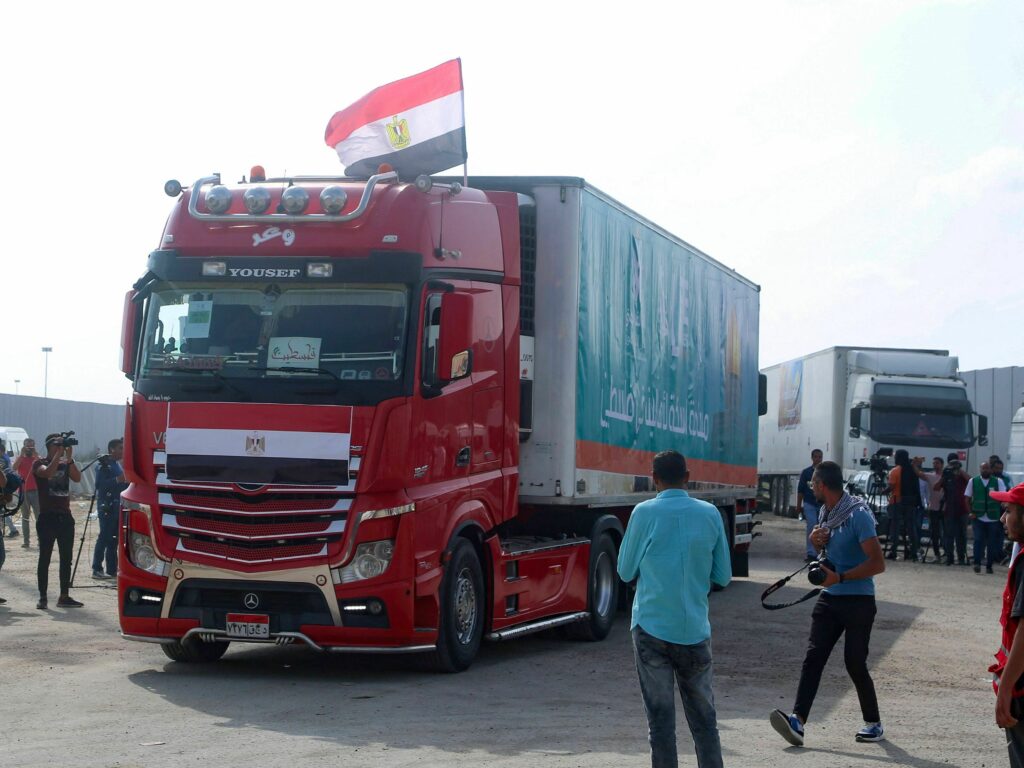 People on the Egyptian side of the Rafah border crossing watch as a convoy of trucks carrying humanitarian aid prepares to cross to the Gaza Strip on Sunday.