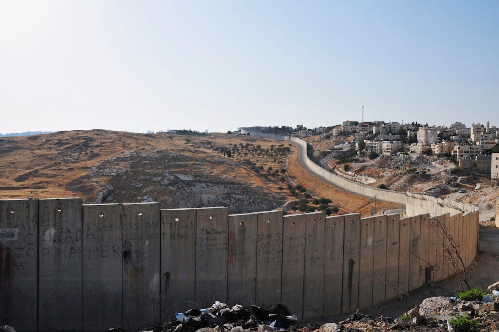 A view of the barrier wall separating Abu Dis from an open filed on the edge of Jerusalem