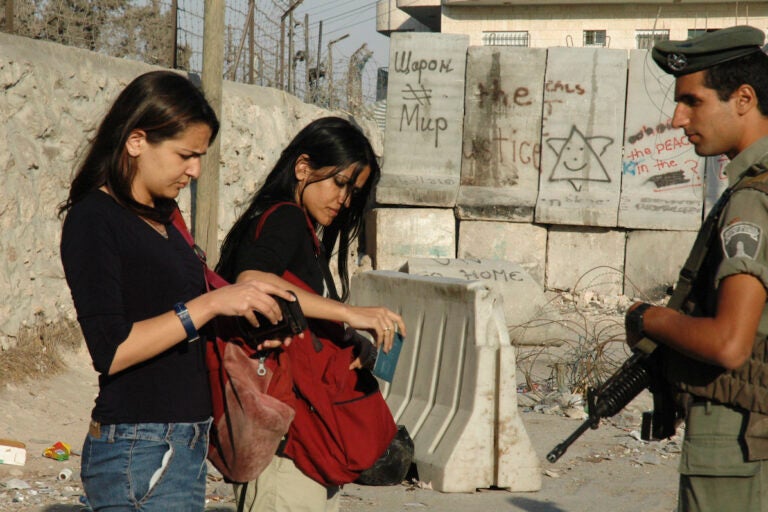 Two women have their IDs checked at the barrier wall between Abu Dis and East Jerusalem