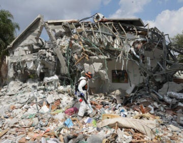 An Israeli soldier walks by a house destroyed by Hamas militants in Kibbutz Be'eri