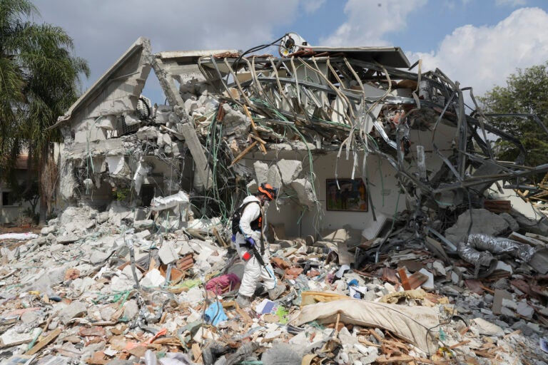 An Israeli soldier walks by a house destroyed by Hamas militants in Kibbutz Be'eri