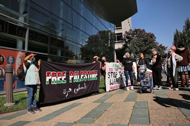 Protesters holding a large sign that says 'Free Palestine'