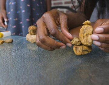 a close-up of a parent and child playing with rocks.