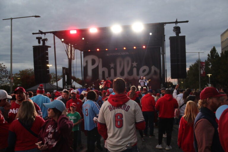 Phillies fans line up in front of a stage with a sign that reads 