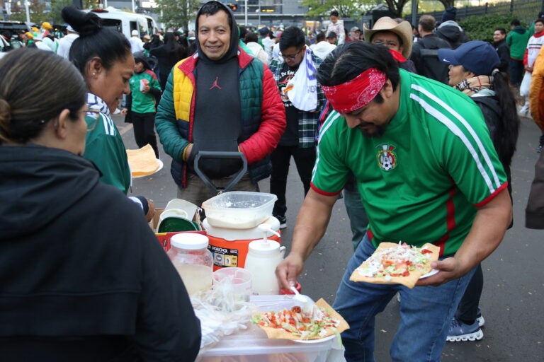 A person scoops toppings on a tostada